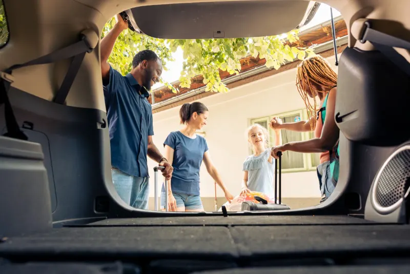 Familia cargando el equipaje en el maletero del coche antes de un viaje